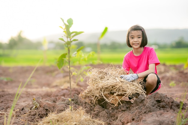 Niños plantando el árbol en tierra y fondo de naturaleza borrosa