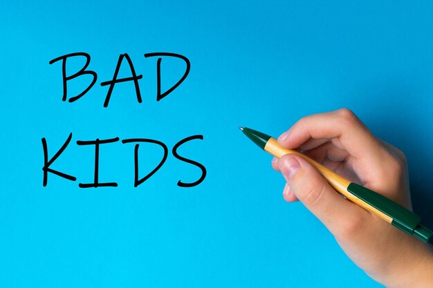 Foto niños con pluma escriben a mano en un fondo blanco azul escribiendo palabras a mano niños malos