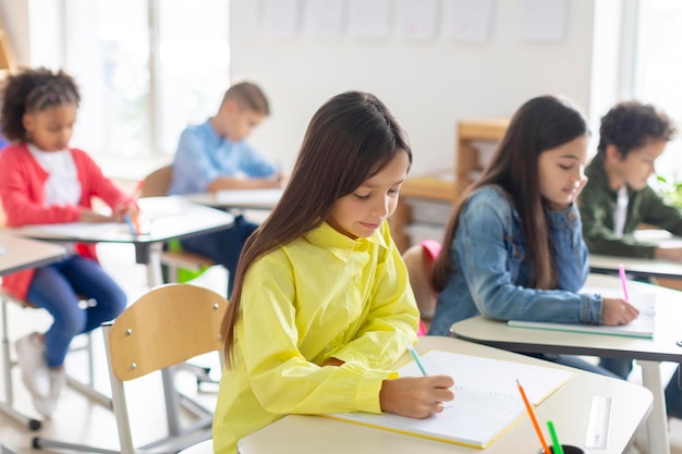 Niños de primaria escribiendo en sus cuadernos de examen creando una atmósfera estudiosa en