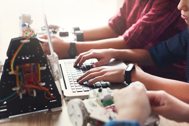 Los niños que crean robots en la escuela, educan, copian el espacio. Manos escribiendo en el teclado, primer plano. Desarrollo temprano, bricolaje, innovación, concepto de tecnología moderna.