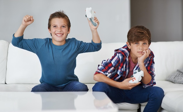 Foto los niños que juegan videojuegos celebran y los amigos juegan con deportes tecnológicos y entretenimiento con el ganador. los niños gamer juegan juegos en la consola en casa felices con la victoria y los niños varones se divierten juntos.