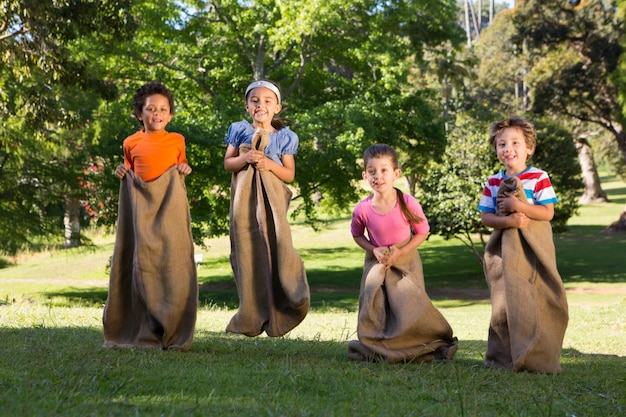 Niños que tienen una carrera de sacos en el parque