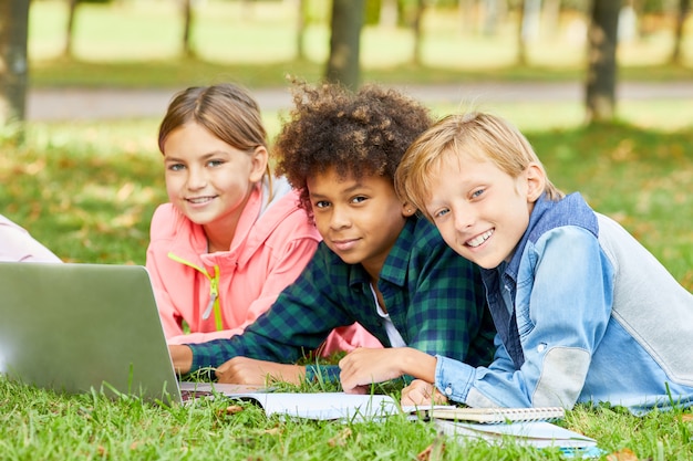 Niños que usan la computadora portátil al aire libre