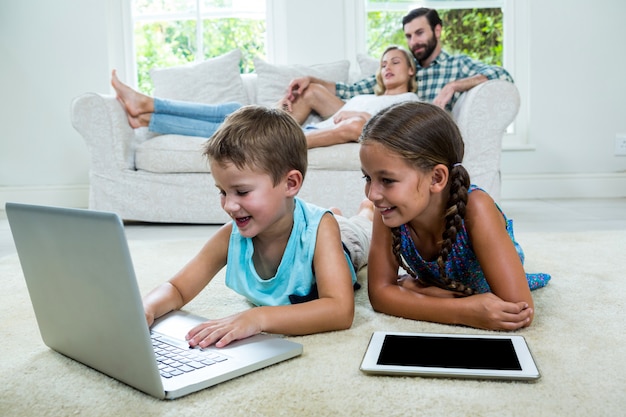 Niños que usan una computadora portátil frente a los padres en casa