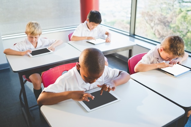 Niños que usan tabletas digitales en el aula