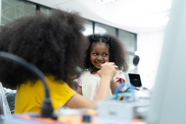 Niños que usan la tecnología de robots manuales y se divierten Aprendiendo la placa de circuito electrónico de la tecnología de robots manuales, que es uno de los cursos STEM