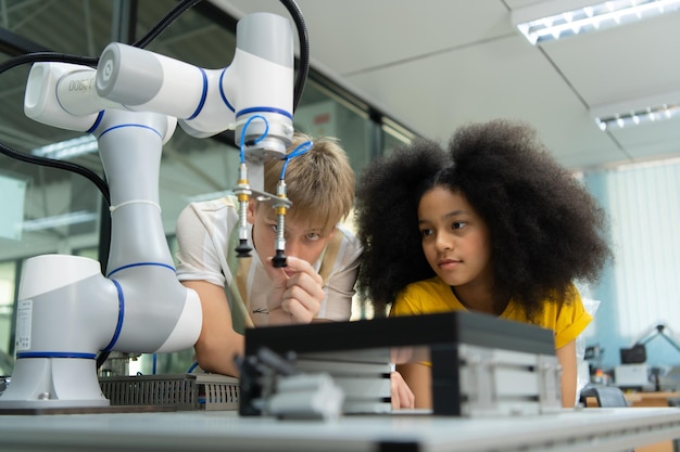 Niños que usan la tecnología de robots manuales y se divierten Aprendiendo la placa de circuito electrónico