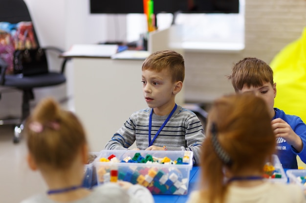 Los niños recogen varios objetos de piezas de plástico del constructor en la escuela de tecnologías digitales.