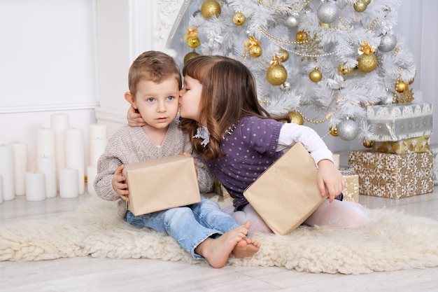 Niños con regalos bajo el árbol de Navidad.