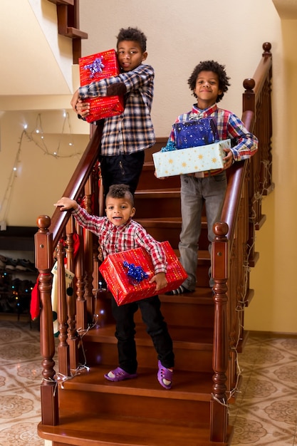 Niños con regalos en las escaleras tres niños con regalos de navidad día festivo favorito de los niños ...