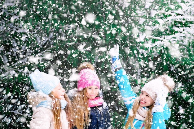 Niños rubios felices entre los árboles nevados