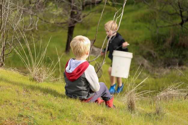 Niños rubios preparándose para pescar con una red de mano en la naturaleza