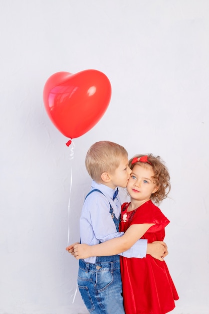 Niños de San Valentín. Niño besa a niña de cinco años con corazón de bola roja