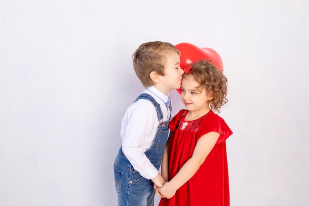 Niños de San Valentín. Niño besa a niña de cinco años con corazón de bola roja