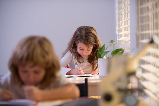 Niños sentados en el escritorio en el aula de la escuela y prueba de escritura.