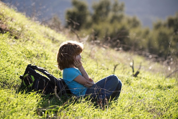 Niños sentados en la hierba alta y admirando las hermosas vistas de las montañas y la naturaleza, un niño y una niña en la cordillera del césped y el fondo del bosque