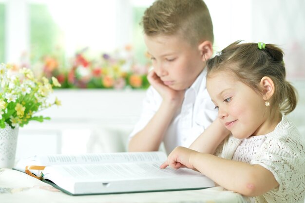 Foto niños sentados a la mesa y leyendo