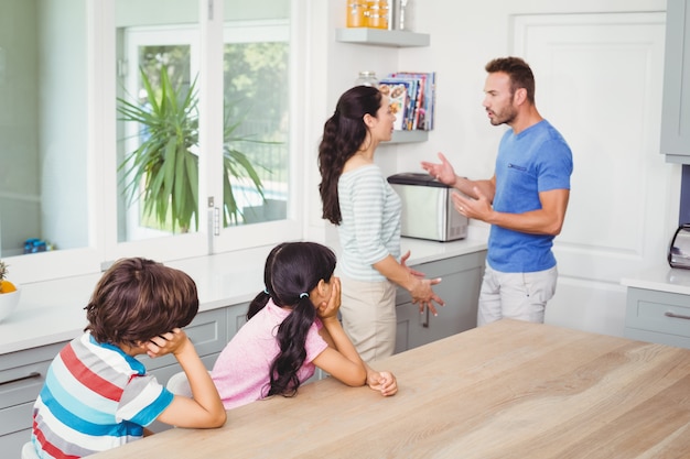 Niños sentados a la mesa con los padres peleándose