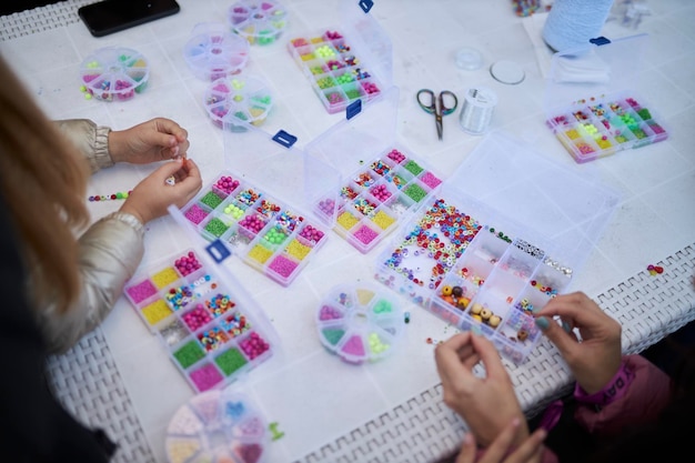 Foto los niños sentados en la mesa recogen pulseras de cuentas multicolores y vista superior de cuentas