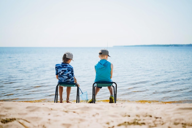 Niños sentados en sillas turísticas pescando en el lago