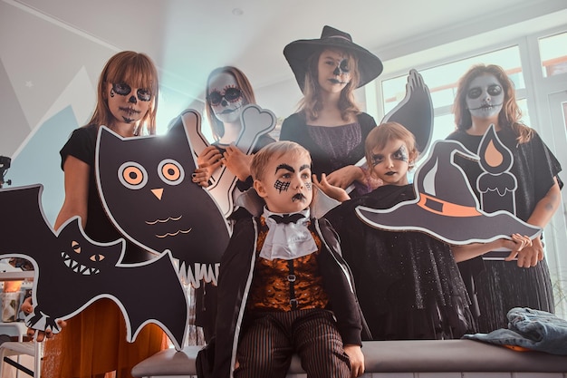 Foto niños serios con disfraces de halloween posan para el fotógrafo con decoraciones festivas en las manos.