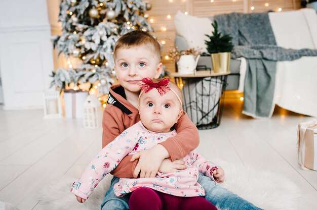 Los niños se sientan en el piso cerca del árbol de Navidad Feliz Año Nuevo y Feliz Navidad