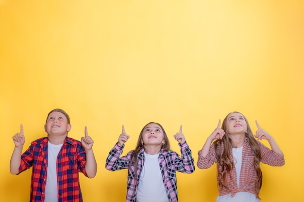 Foto niños sobre un fondo amarillo apuntan hacia arriba