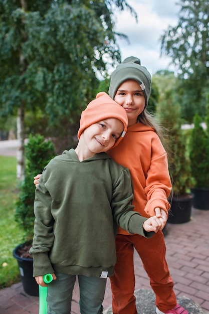 Niños con sombreros de moda y sudaderas con capucha divirtiéndose en el parque otoño vibraciones otoño estilo de belleza moda infantil