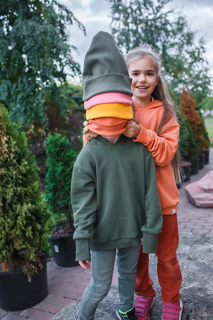 Niños con sombreros de moda y sudaderas con capucha divirtiéndose en el parque otoño vibraciones otoño estilo de belleza moda infantil