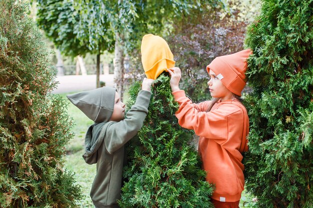 Niños con sombreros de moda y sudaderas con capucha divirtiéndose en el parque otoño vibraciones otoño estilo de belleza moda infantil