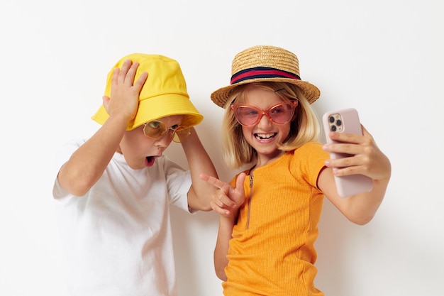 Niños con sombreros con teléfono juntos amistad