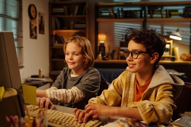 Niños sonrientes disfrutando de un juego de computadora en una habitación acogedora