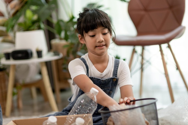 Niños sonrientes divirtiéndose mientras segregan botellas de plástico y papel en una papelera