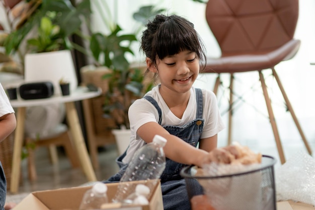 Niños sonrientes divirtiéndose mientras segregan botellas de plástico y papel en una papelera