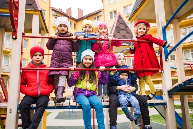 Los niños sonrientes están parados juntos en el equipo del patio