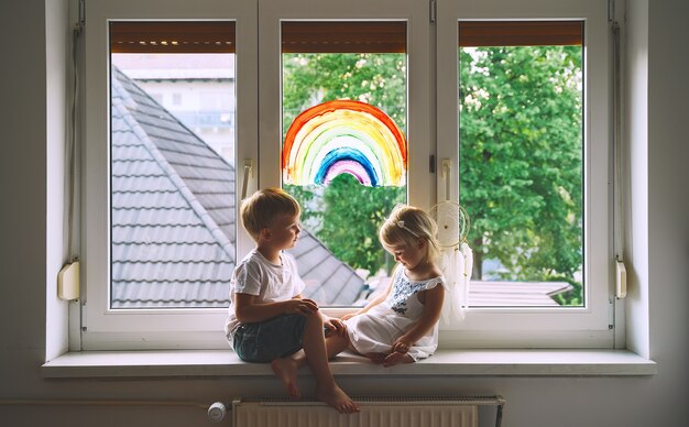 Niños sonrientes en el fondo de la pintura del arco iris en la ventana