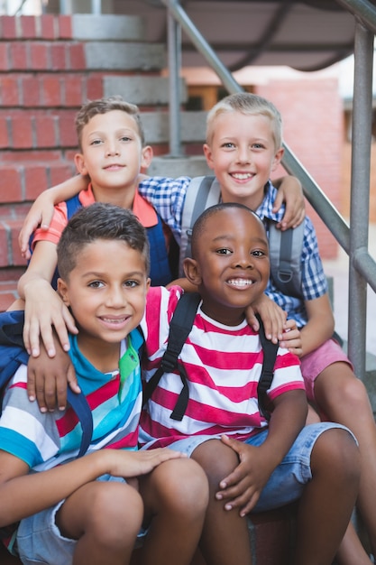 Niños sonrientes sentados en la escalera en la escuela