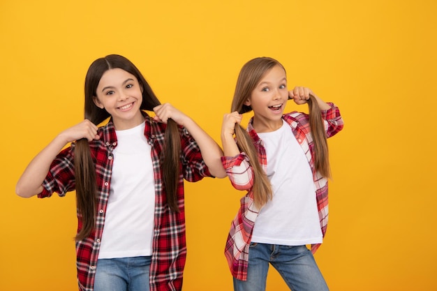 Los niños sonrientes sostienen la belleza del cabello largo y lacio y la moda femenina modelo de moda jovencitas en camisas casuales a cuadros retrato de niños amigos expresan emociones positivas amistad
