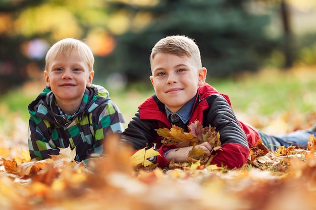 Niños sonrientes en el suelo con hojas de otoño