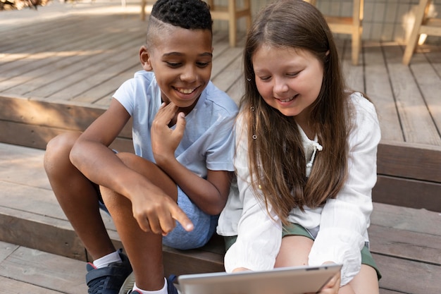 Niños sonrientes con tableta de tiro medio