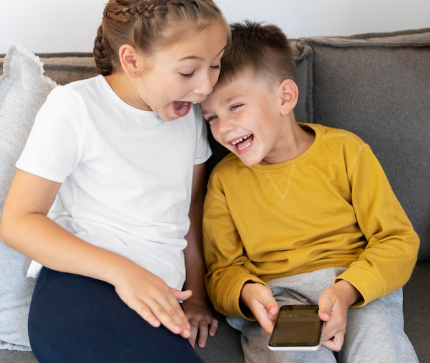 Foto niños sonrientes de tiro medio con teléfono