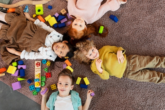 Foto niños sonrientes de vista superior acostados juntos en el piso