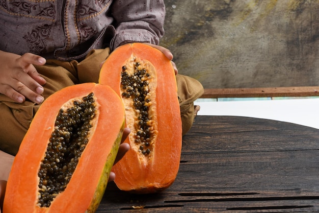 los niños sostienen la mitad de la fruta de papaya