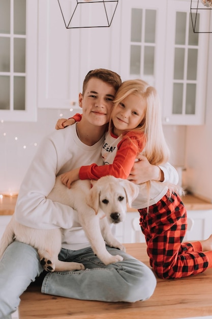 Los niños con su amado perro están sentados en la cocina navideña. pasatiempo familiar. estilo de vida. hermano y hermana, niño y niña juegan y juegan con una mascota. espacio para texto. foto de alta calidad