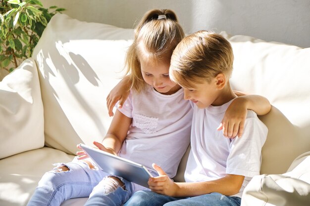 Niños con tablet pc en el sofá de la sala de estar