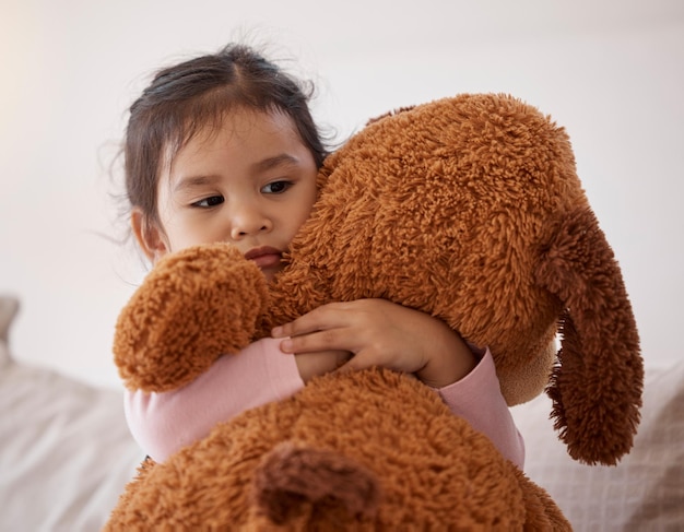 Los niños temen y asustan a una niña que sostiene a su osito de peluche después de una pesadilla en su dormitorio en casa. Los niños tienen ansiedad y depresión a una niña pequeña que abraza un animal de peluche en su casa.