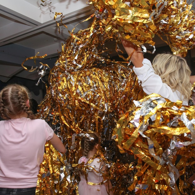 los niños se tiran papel dorado en rodajas entre sí