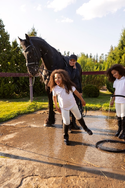 Niños de tiro completo aprendiendo a montar a caballo.