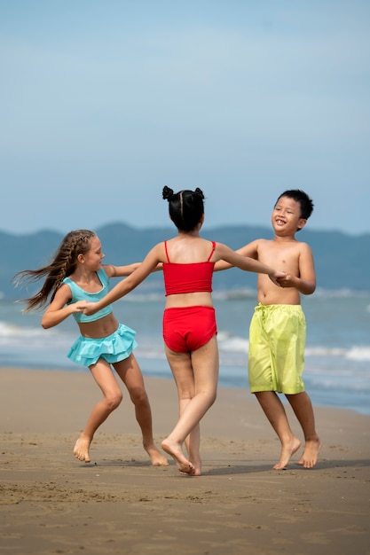 Niños de tiro completo bailando en la playa