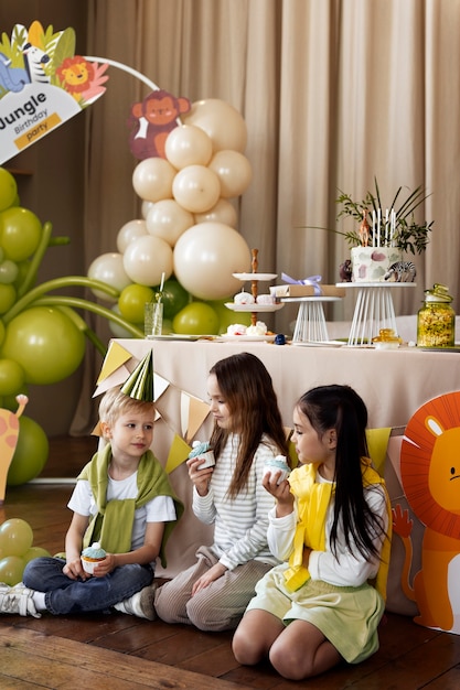 Foto niños de tiro completo comiendo cupcakes